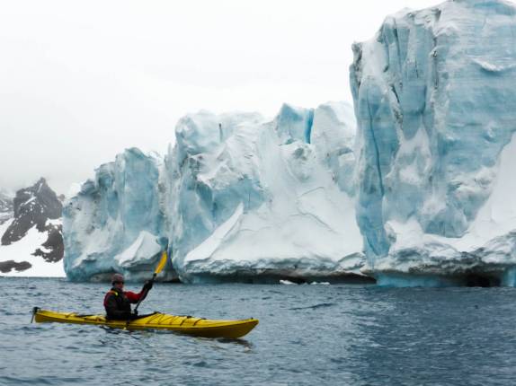 Remando ao lado das peredes monumentais de gelo de uma geleira em Brown Bluff, na Antártida